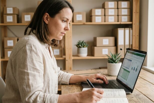 Entrepreneuse gérant la comptabilité de sa boutique en ligne depuis son bureau à domicile avec tableur et notes manuscrites