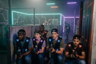 Équipe de collègues en pleine partie de laser game mobile à Lyon, portant des vestes tactiques dans une arène néon