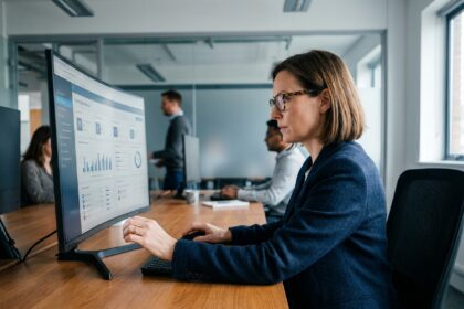 Responsable RH analysant un plan de formation centralisé sur un tableau de bord numérique dans un bureau moderne