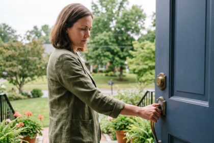 Femme vérifiant le verrou de sa porte d'entrée avant de partir en vacances
